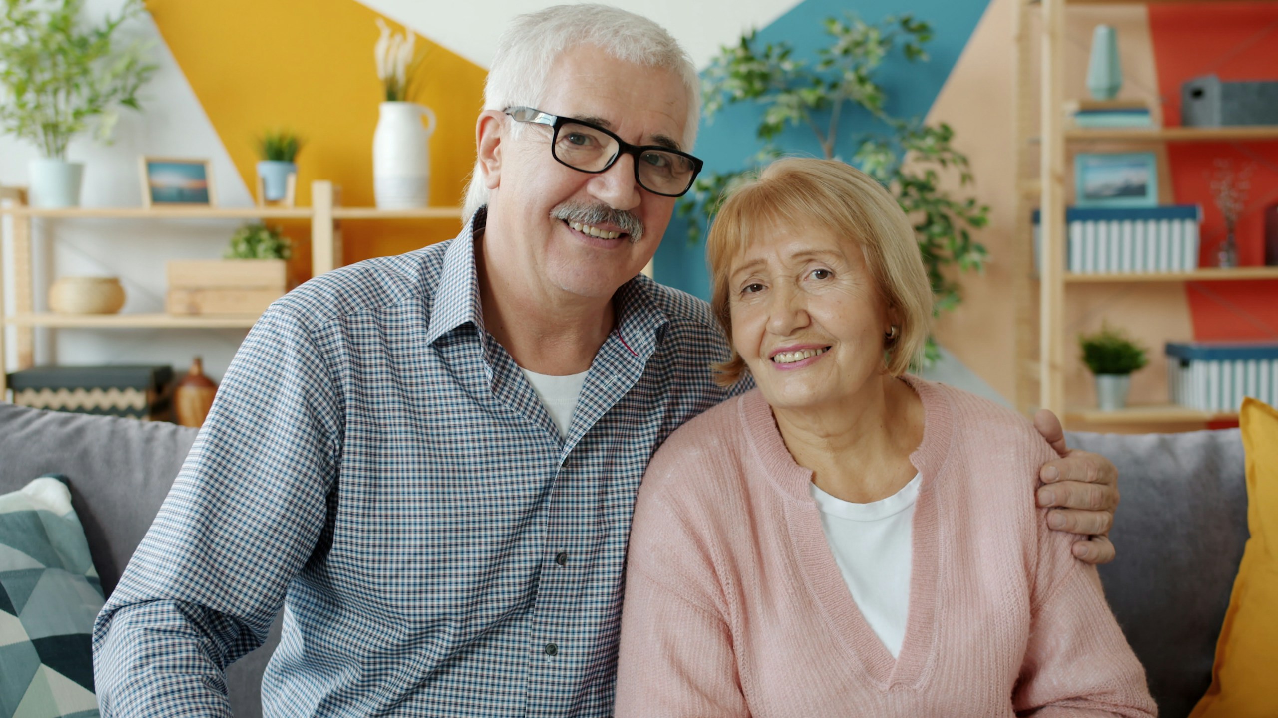 Smiling retired couple sitting together on their living room couch