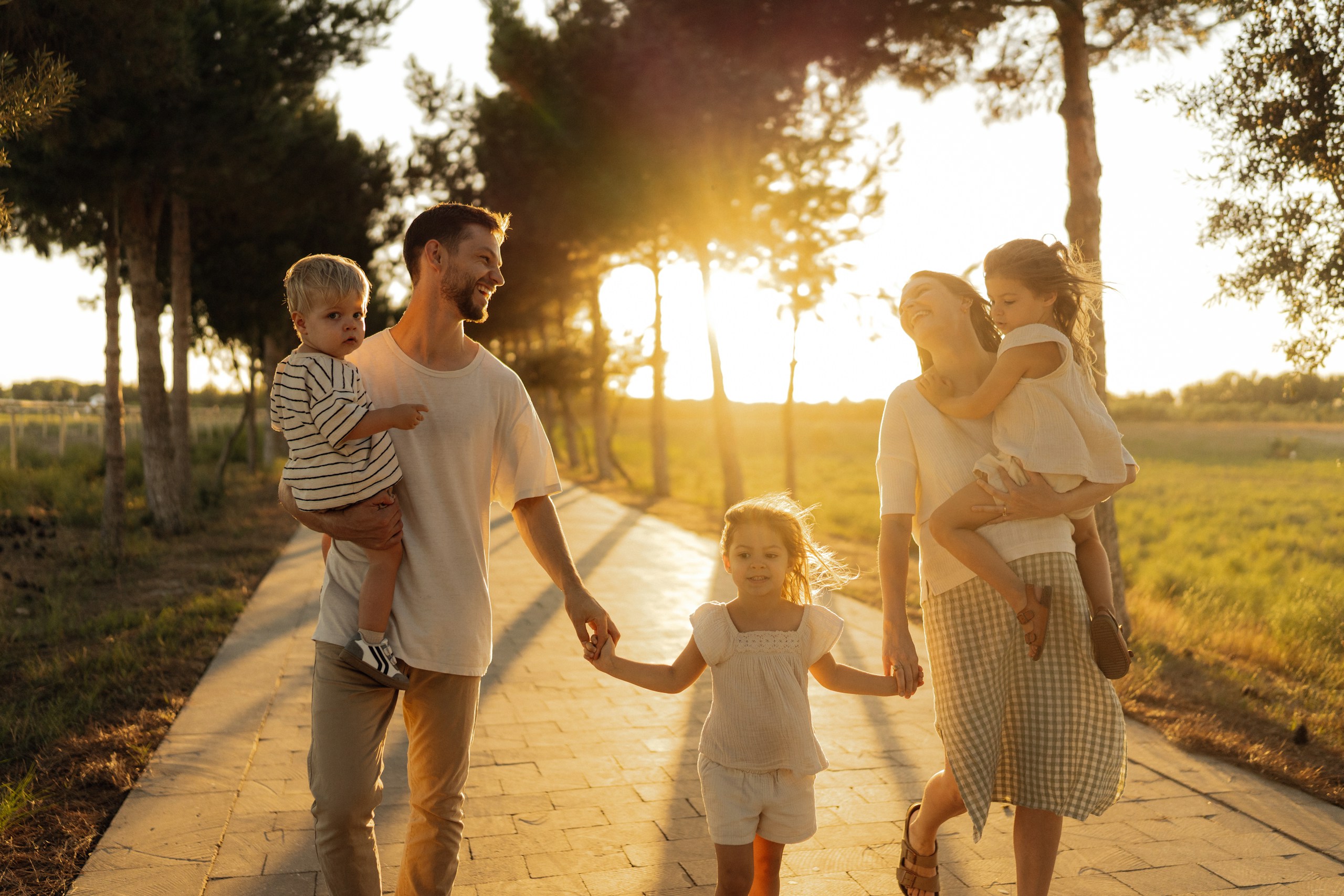 Young family walking hand in hand along a sunlit path