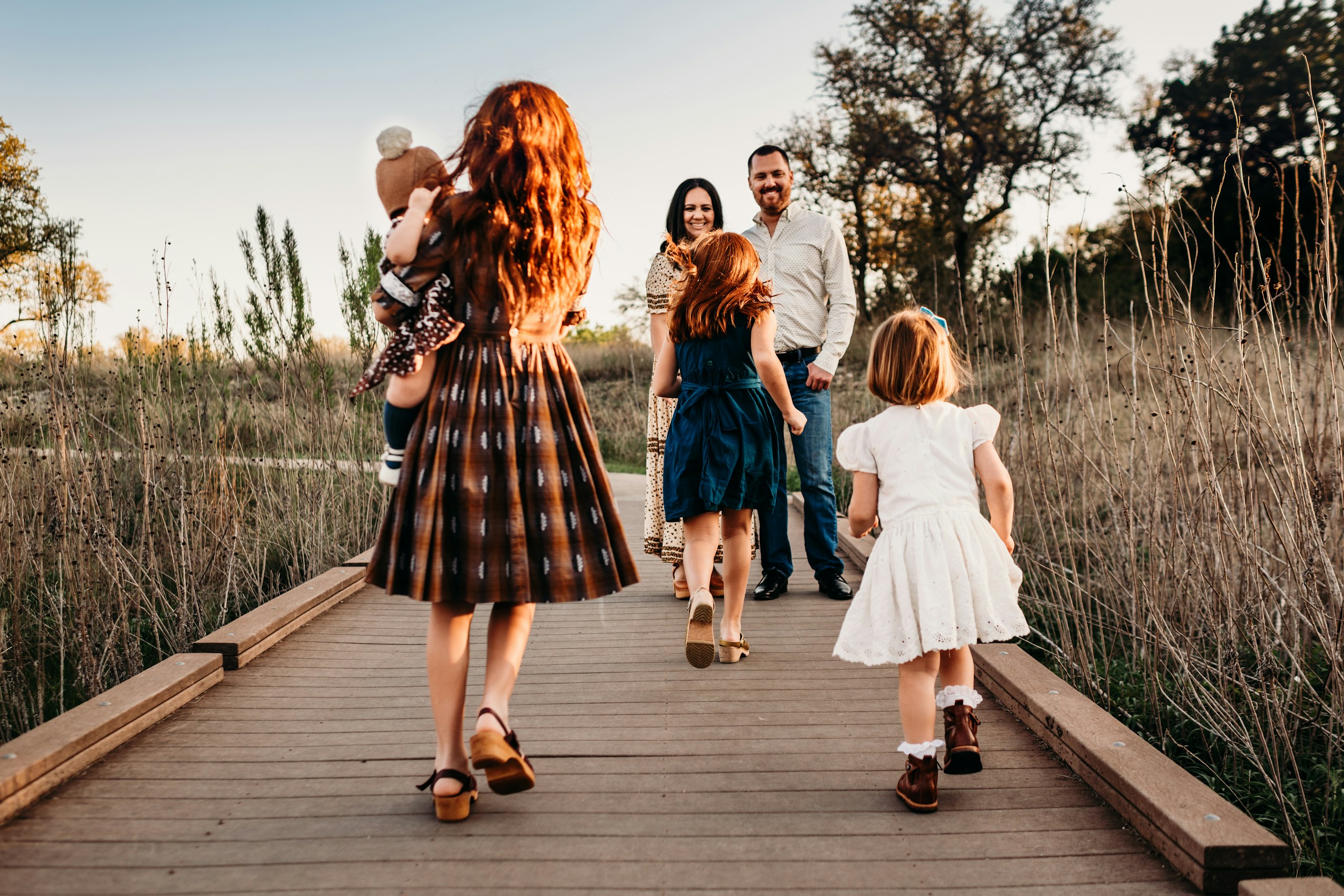 Family walking together along a wooden boardwalk at golden hour