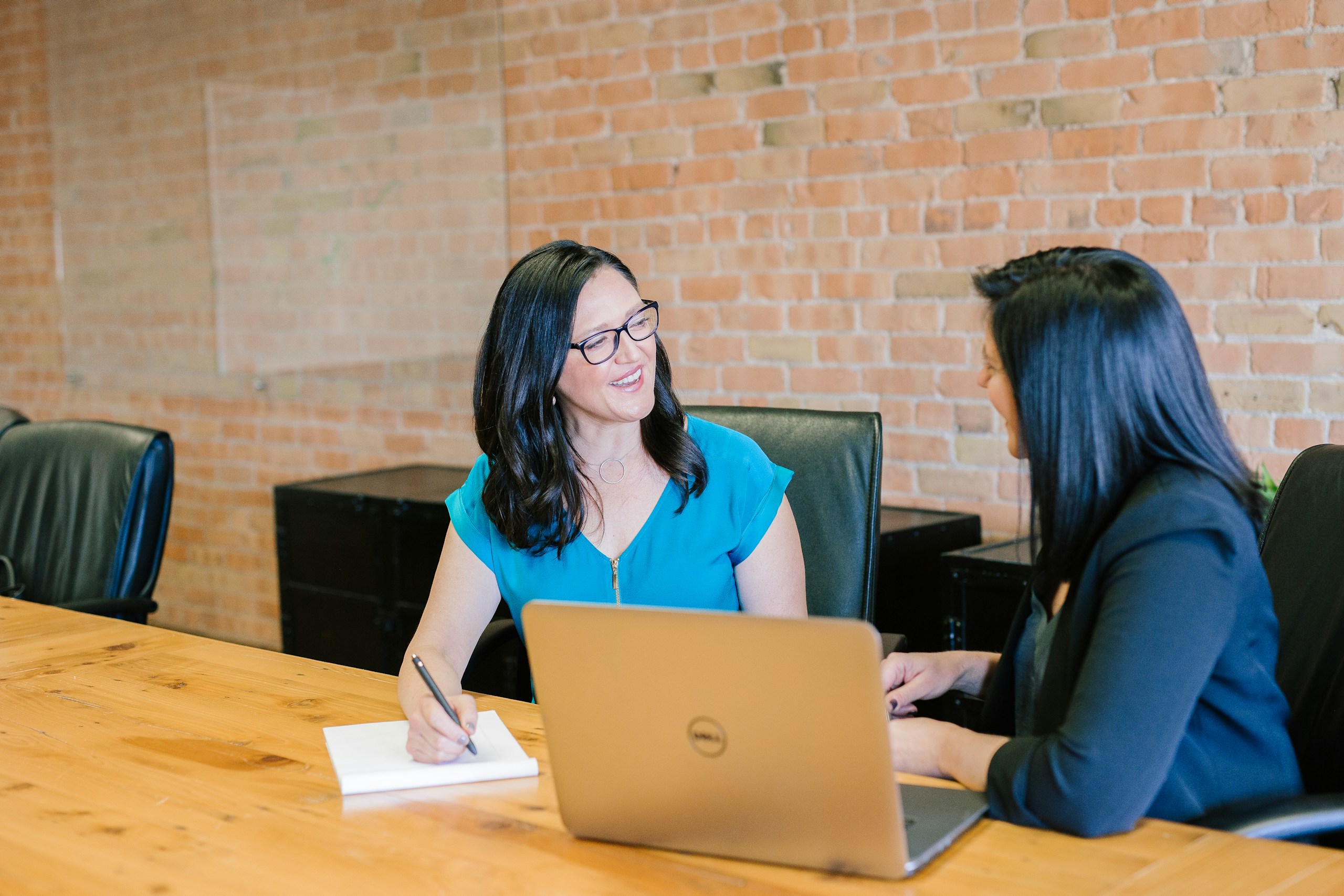 Two women talking through a plan at a table with a laptop