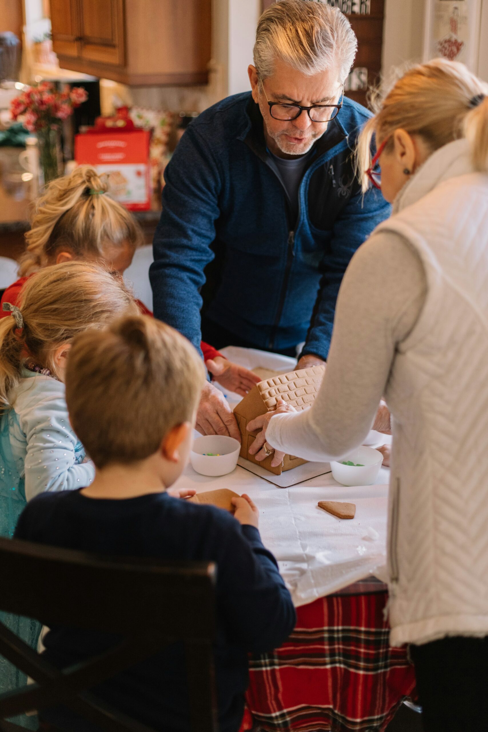 Grandparents making a gingerbread house with their grandchildren