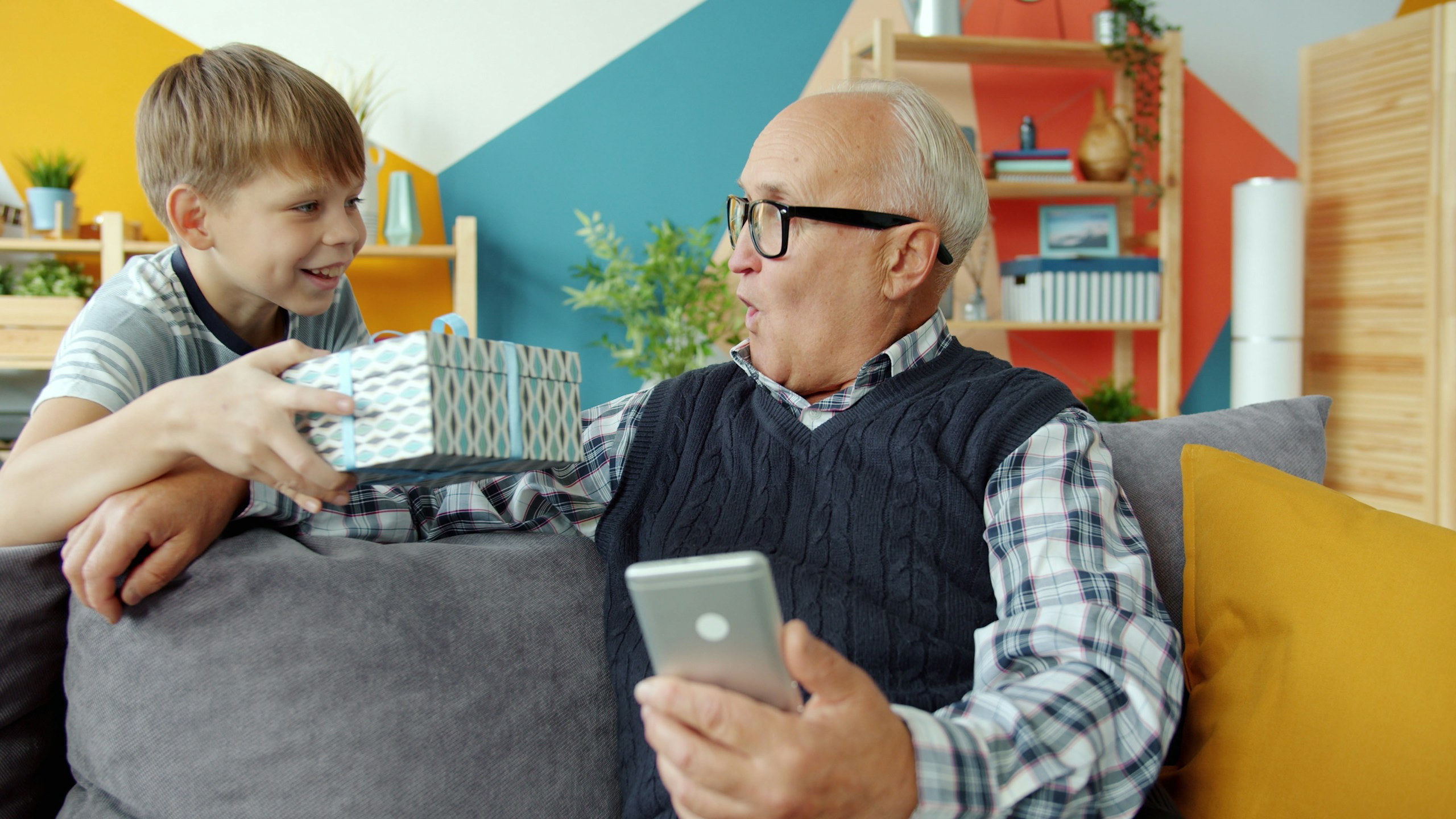 Boy giving his smiling grandfather a gift at home