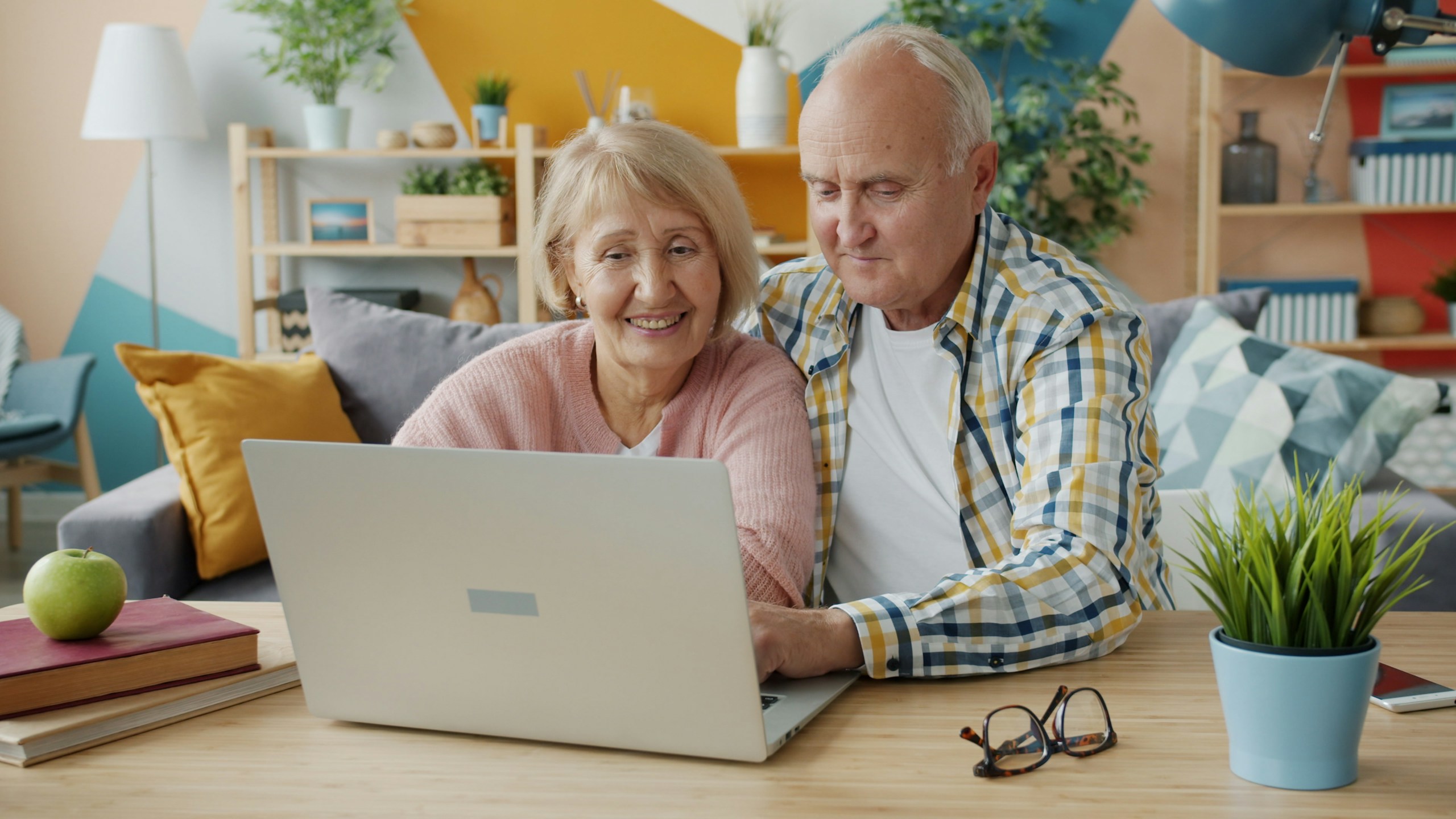 Smiling senior couple reviewing their plans on a laptop at home