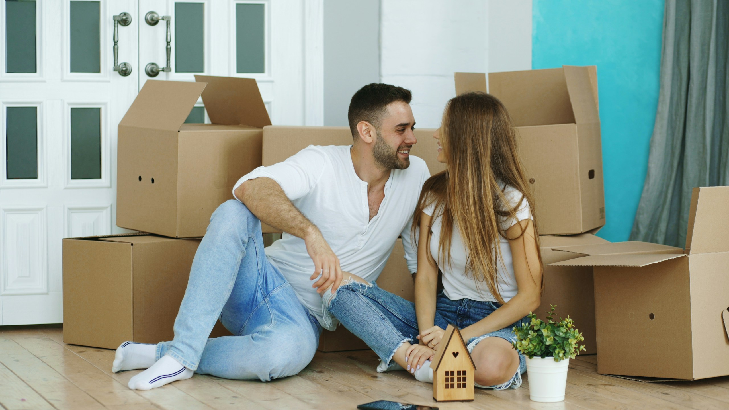 Young couple sitting among moving boxes in their new home